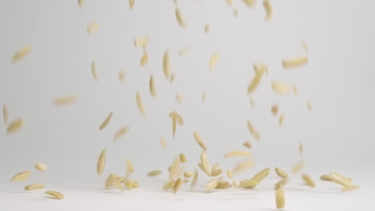 슬로우 모션으로 흰색 배경에 더미로 튀는 원시 아몬드 너트 조각