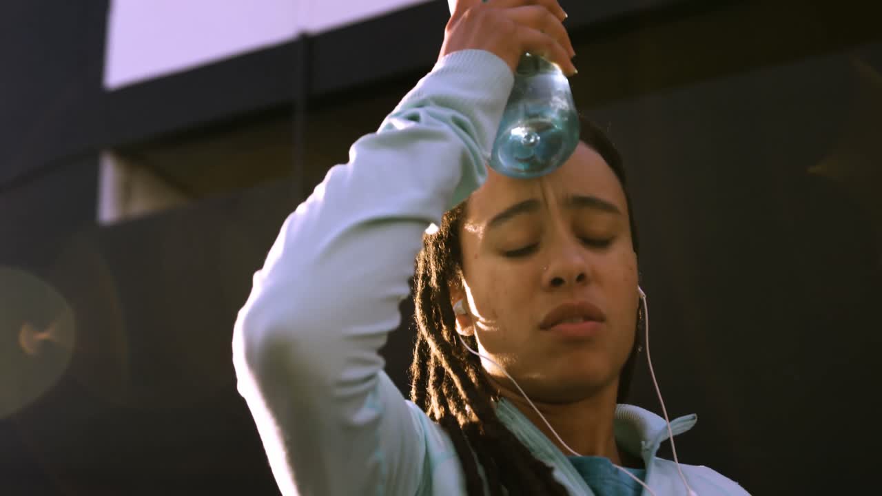 vista frontal de una joven mujer afroamericana descansando después de hacer ejercicio en la ciudad 4k