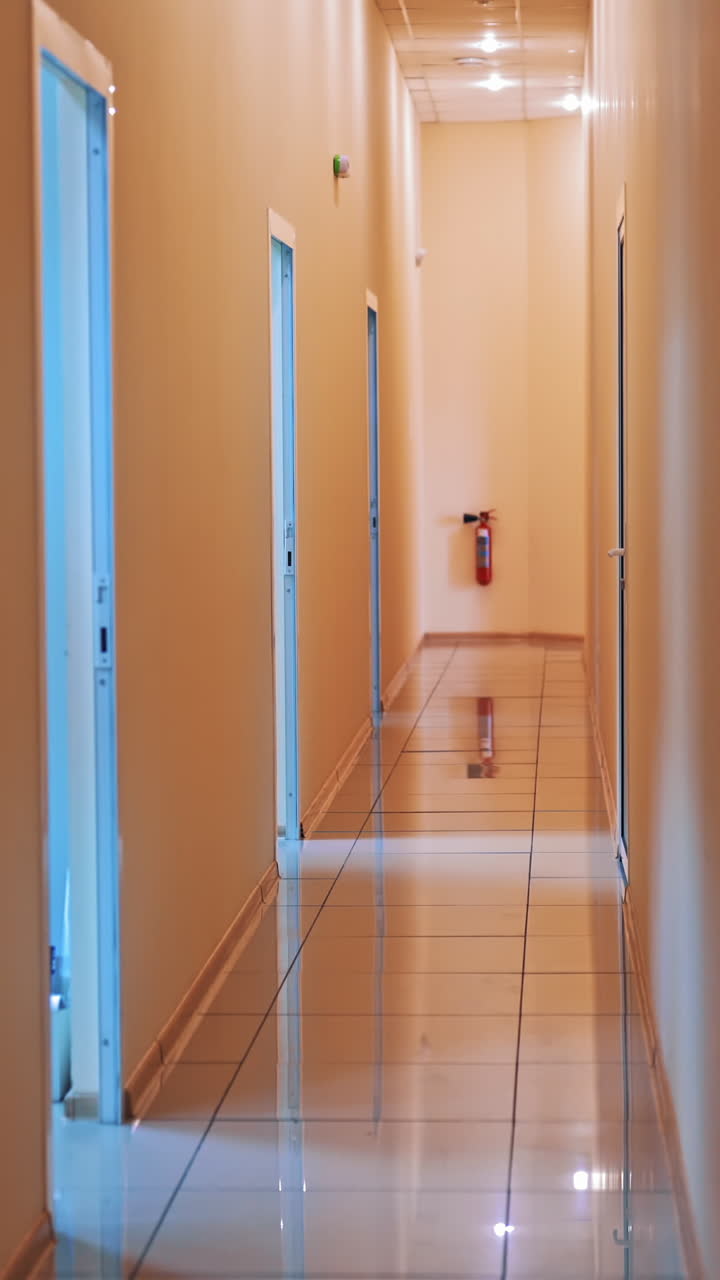 Back view of a man in protective suit and with bag going through the corridor. Male worker is carring out special bag with test tubes from the laboratory. Vertical video