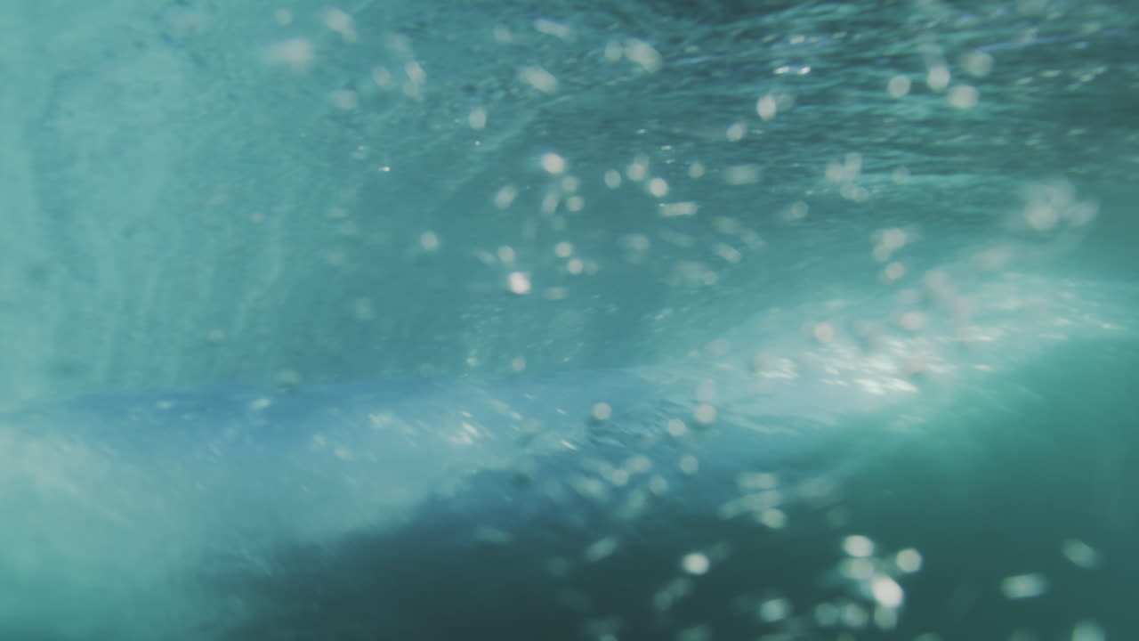 Ripresa al rallentatore di una grande onda oceanica che si arriccia, filmata fuori dall'acqua all'alba, che mostra la superficie liscia dell'onda e la formazione del tubo