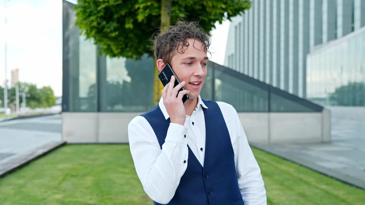 Businessman speaking on phone outside modern office building