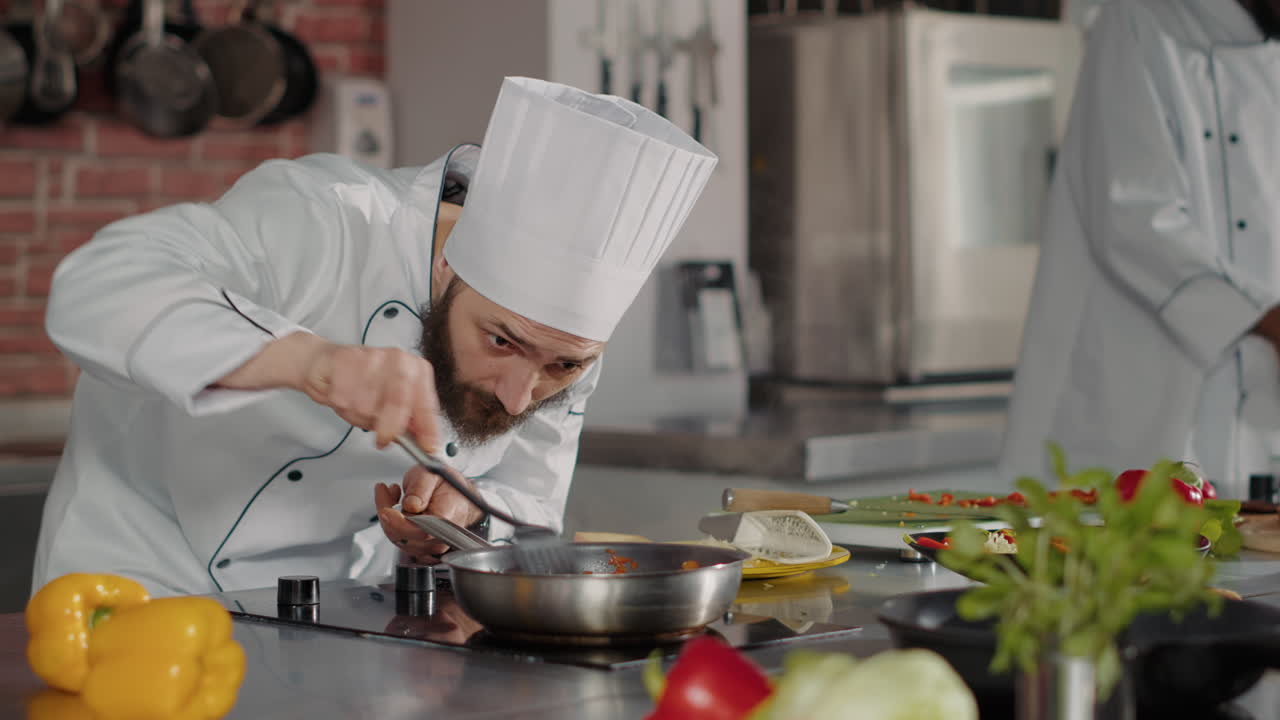 Male chef pouring shredded cheese on cooked food in frying pan