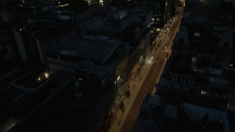 establishing drone shot over leeds city centre streets with man walking at night