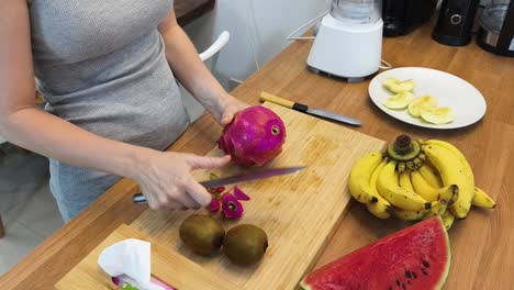 una mujer preparando frutas para un batido.