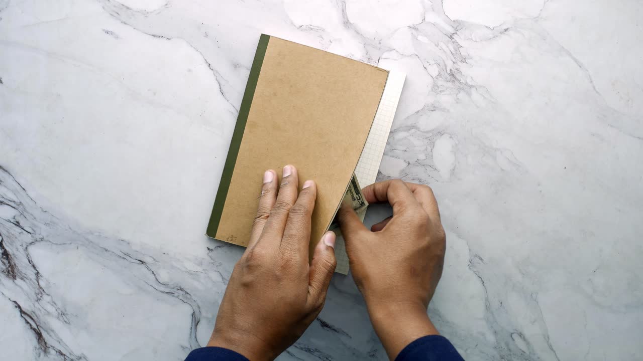Hands Opening a Notebook with Money