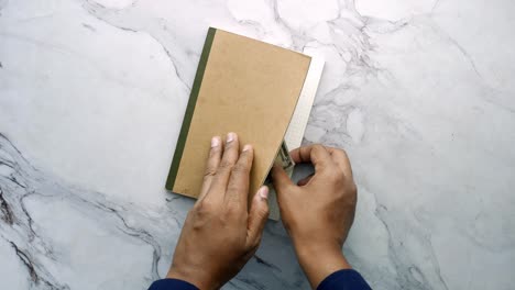 hands opening a notebook with money