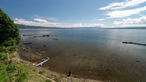 panoramic view of a serene lake with distant mountains and a person on the shore