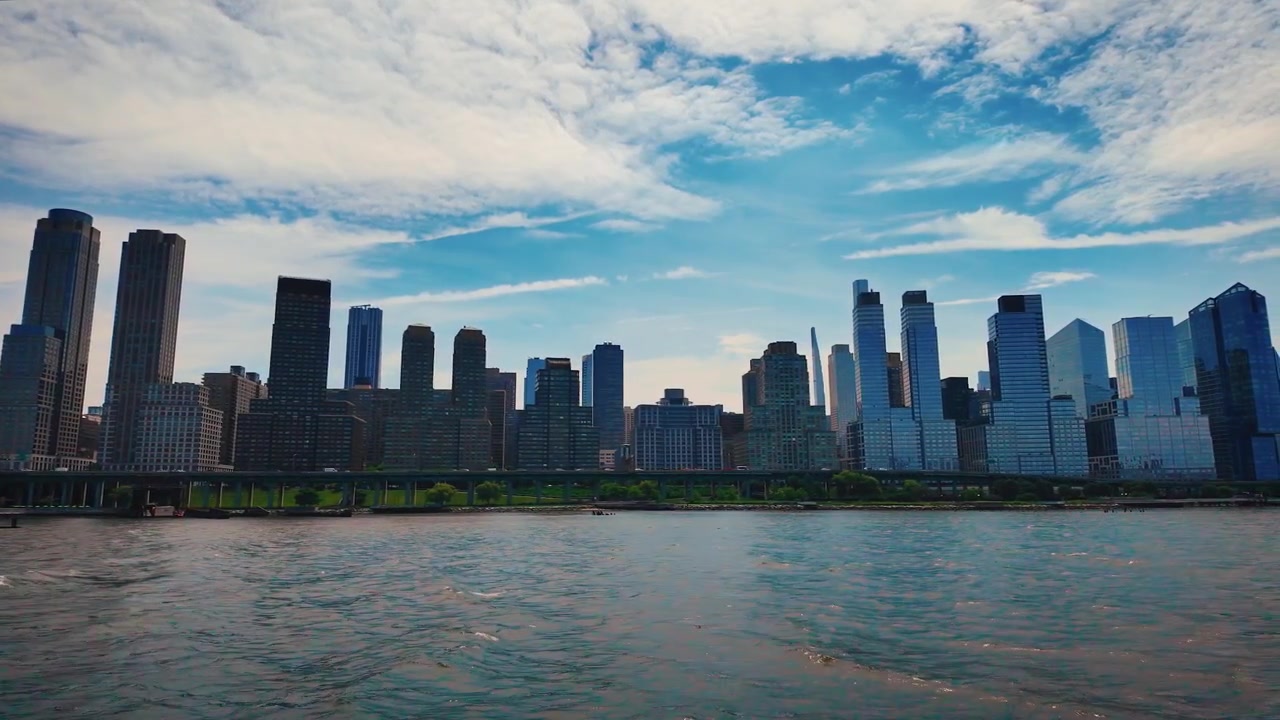Boat cruise past Manhattan featuring Riverside Center, Billionaires' Row, Hudson Yards and modern Midtown skyscrapers under a dramatic blue sky on the Hudson River.