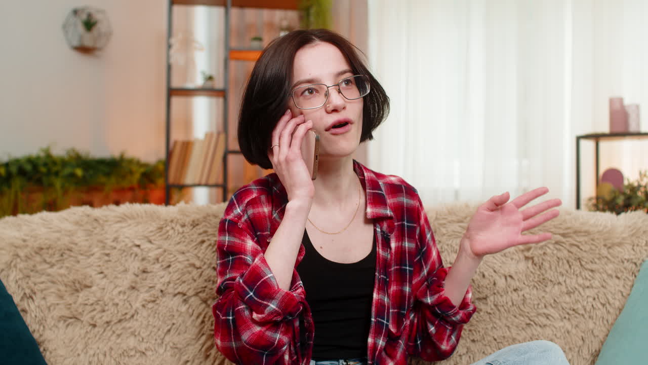 Young woman talking on smartphone smiling with joy and using expressive hand movement during call