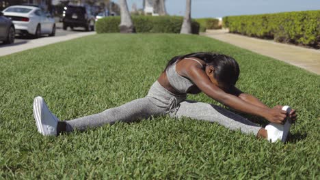 mujer negra estirándose en un parque soleado