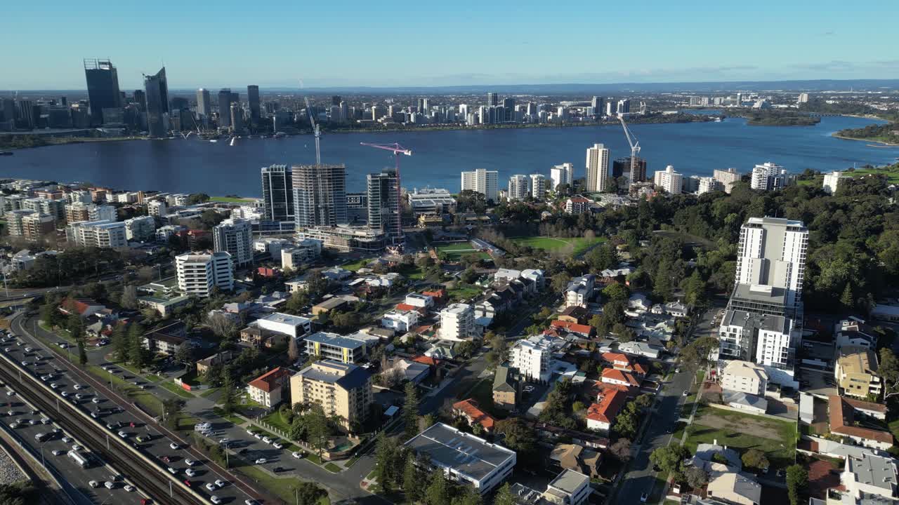 vuelo aéreo lento que muestra el tráfico y el área suburbana de la ciudad de perth a la hora de la puesta del sol y el río swan en el fondo
