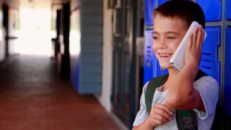 Happy-schoolboy-talking-on-mobile-phone-in-corridor-4k