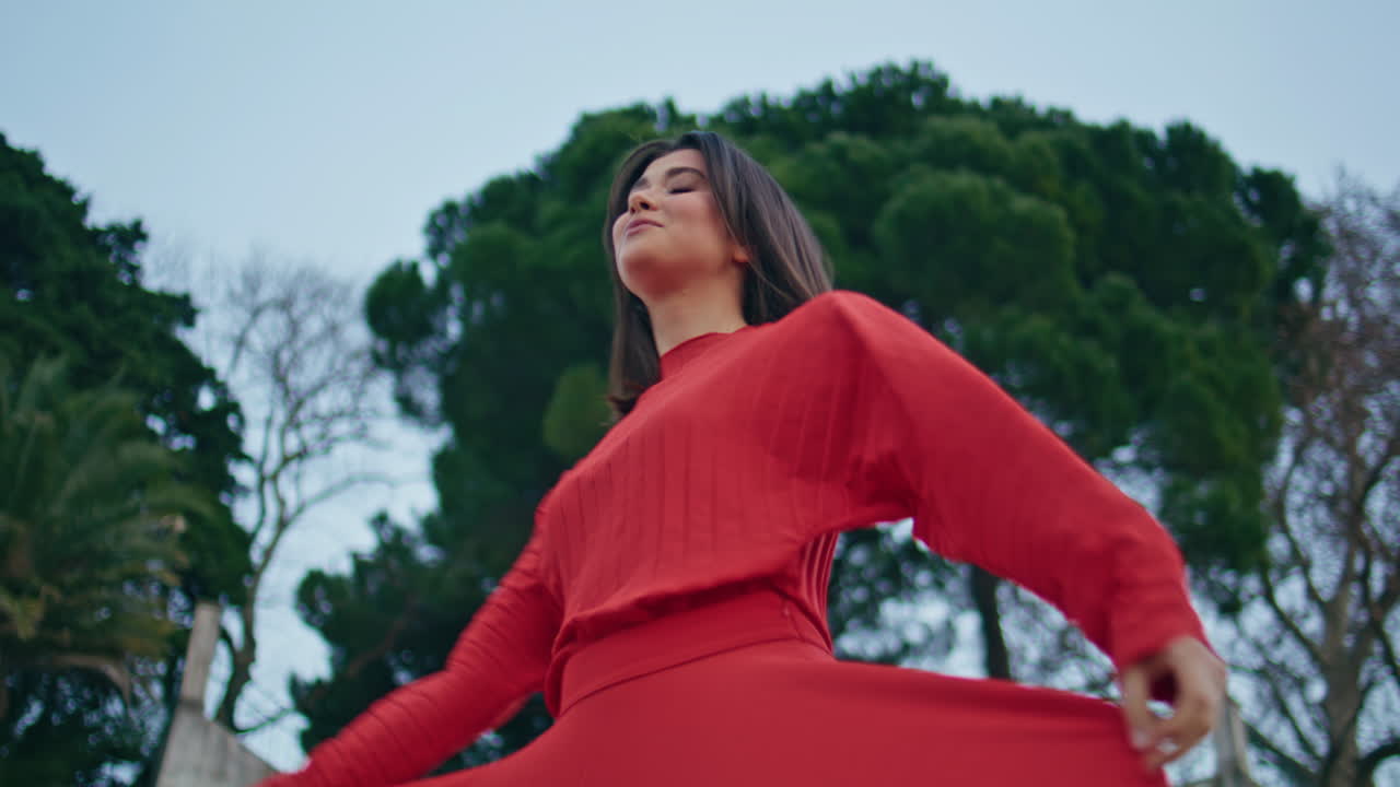 Happy brunette spinning park bottom view. Woman in red dress looking camera