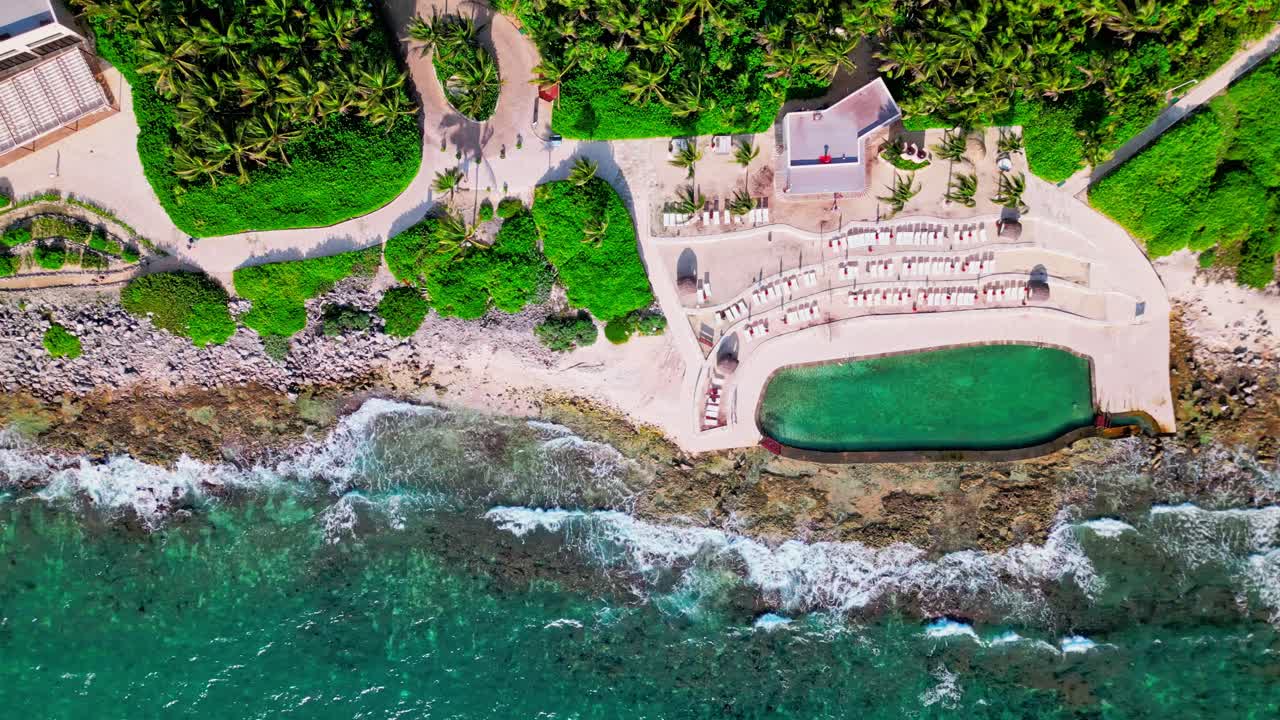 trs yucatan resort en tulum, méxico. vista aérea de la piscina de agua salada y el mar caribe con grandes olas que se estrellan en la playa cerca de la piscina infinita.