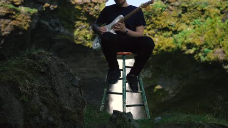 man playing guitar in front of a beautiful waterfall in iceland-9