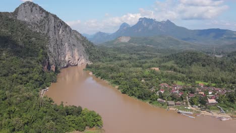 aerial view of mekong river beside local village town and towering cliffs in luang prabang