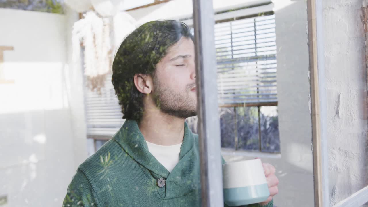 Caucasian man drinking coffee and looking out window at home, slow motion
