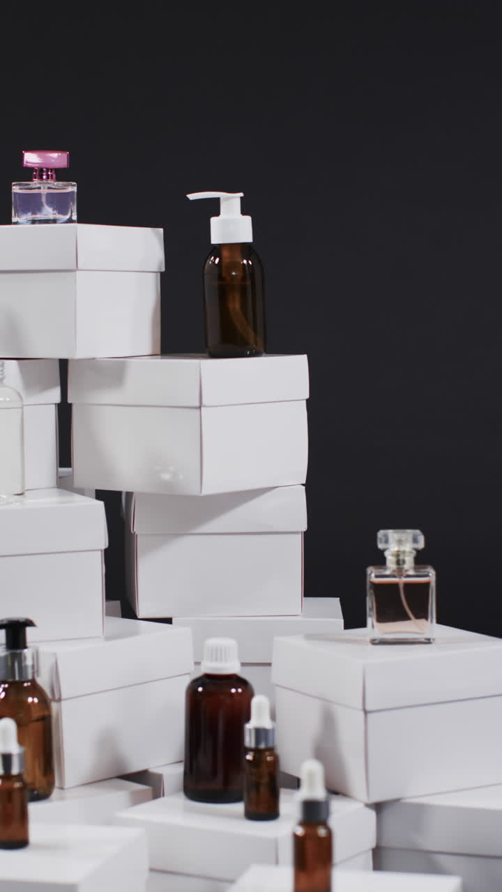 Vertical video of beauty products with white cardboard boxes with copy space over black background