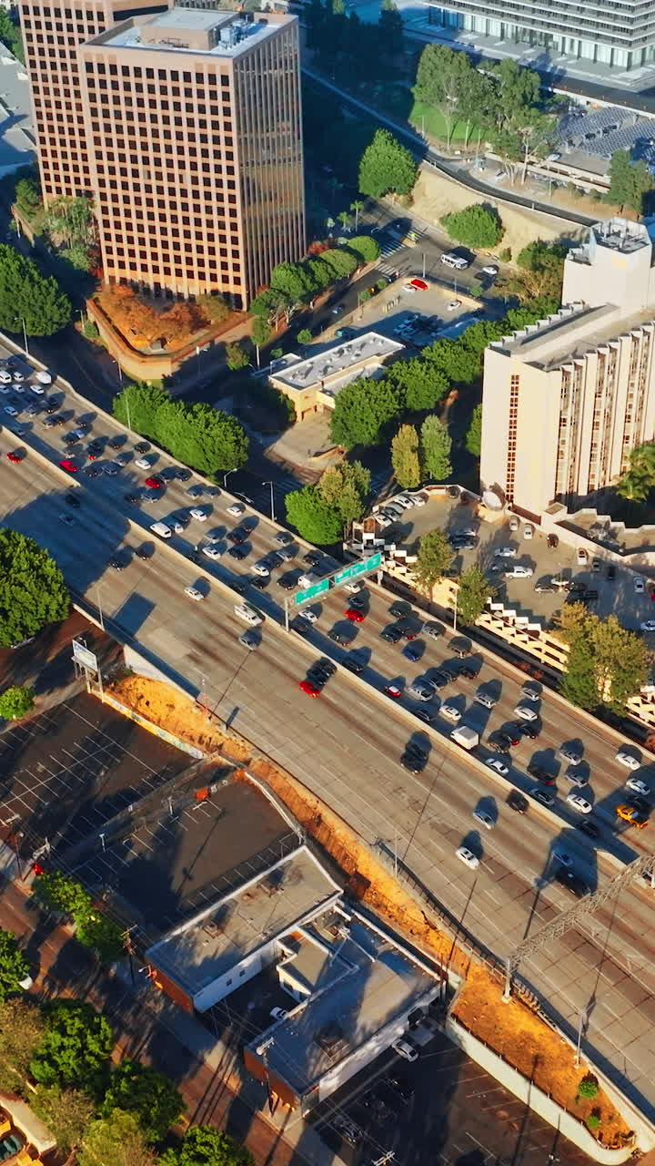 Traffic flow by the wide-lane roads of Los Angeles. Approaching the two-directions highways in the city downtown. Vertical video