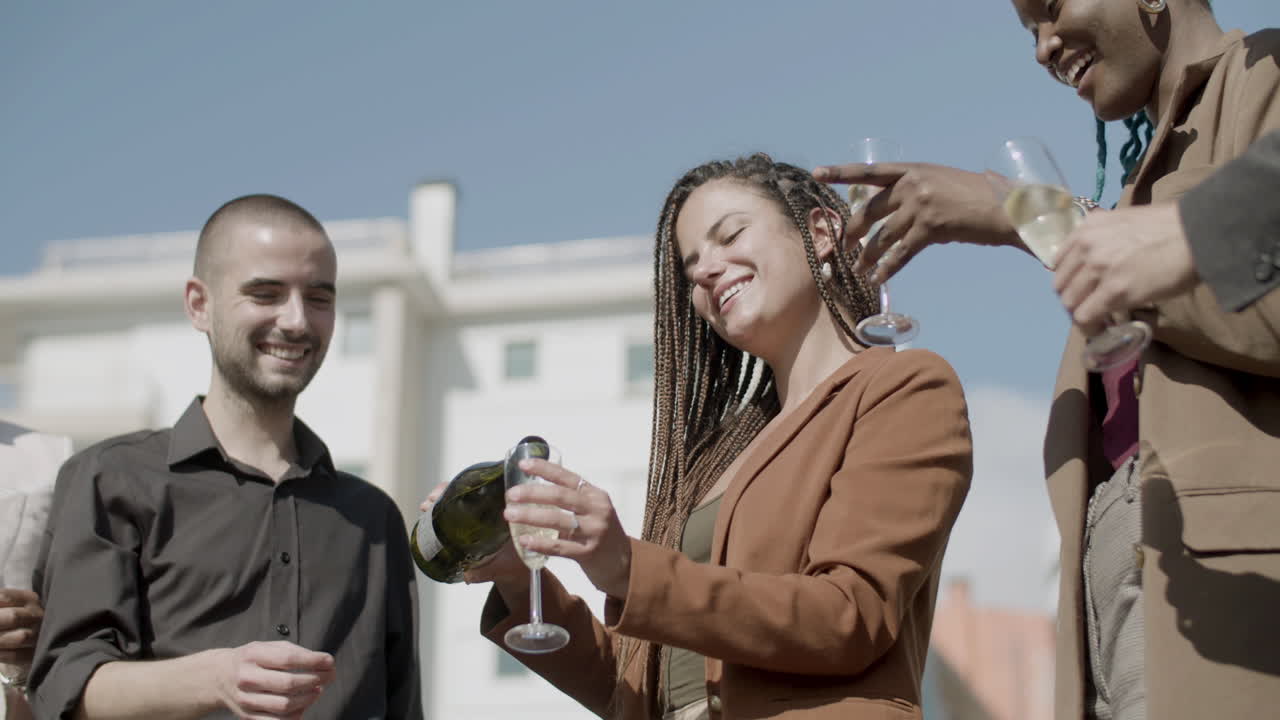 mujer feliz vertiendo champán en copas en una fiesta de negocios