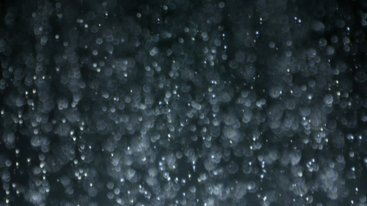 macro de alta velocidad de plato lateral en bucle disparo de lluvia de agua en negro en enfoque selectivo