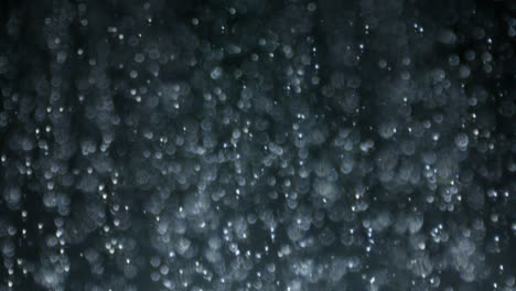 loop-makro-hochgeschwindigkeits-seitplatte-schuss von wasserregen auf schwarz in selektiver fokussierung