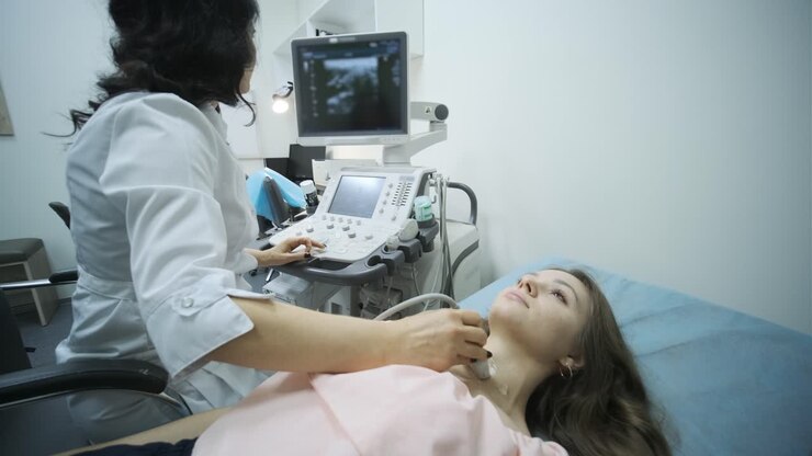 Ultrasound scanning diagnostic of young woman thyroid gland in clinic. Woman doctor runs ultrasound sensor over patient's neck.