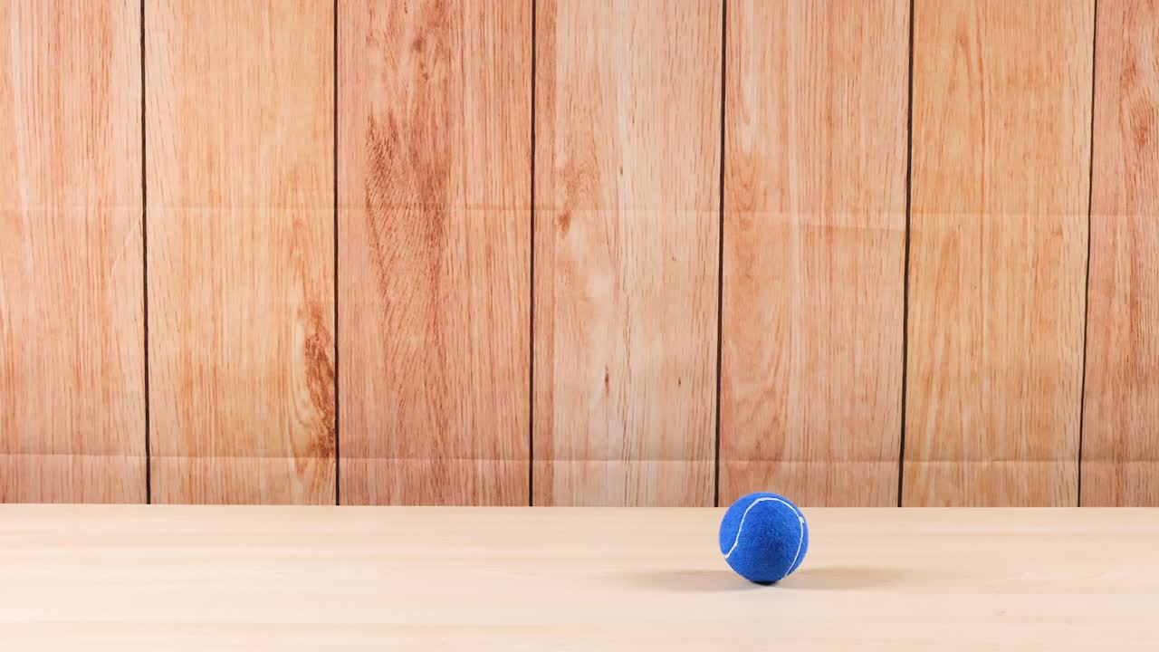 A blue tennis ball moves across a shelf