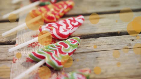 Animation-of-dots-moving-over-christmas-tree-candies-on-wooden-surface