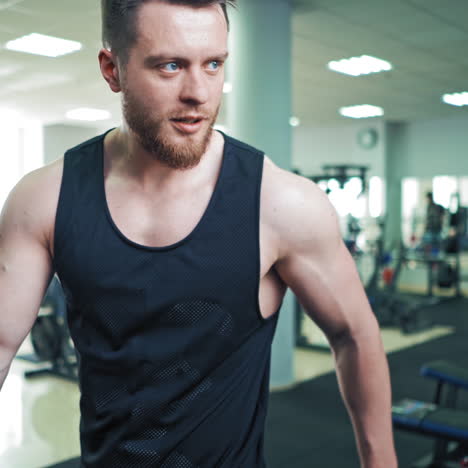 strong athletic man on mirror background in gym. muscular man shows his trained biceps on arms while looking at his reflection in the mirror.