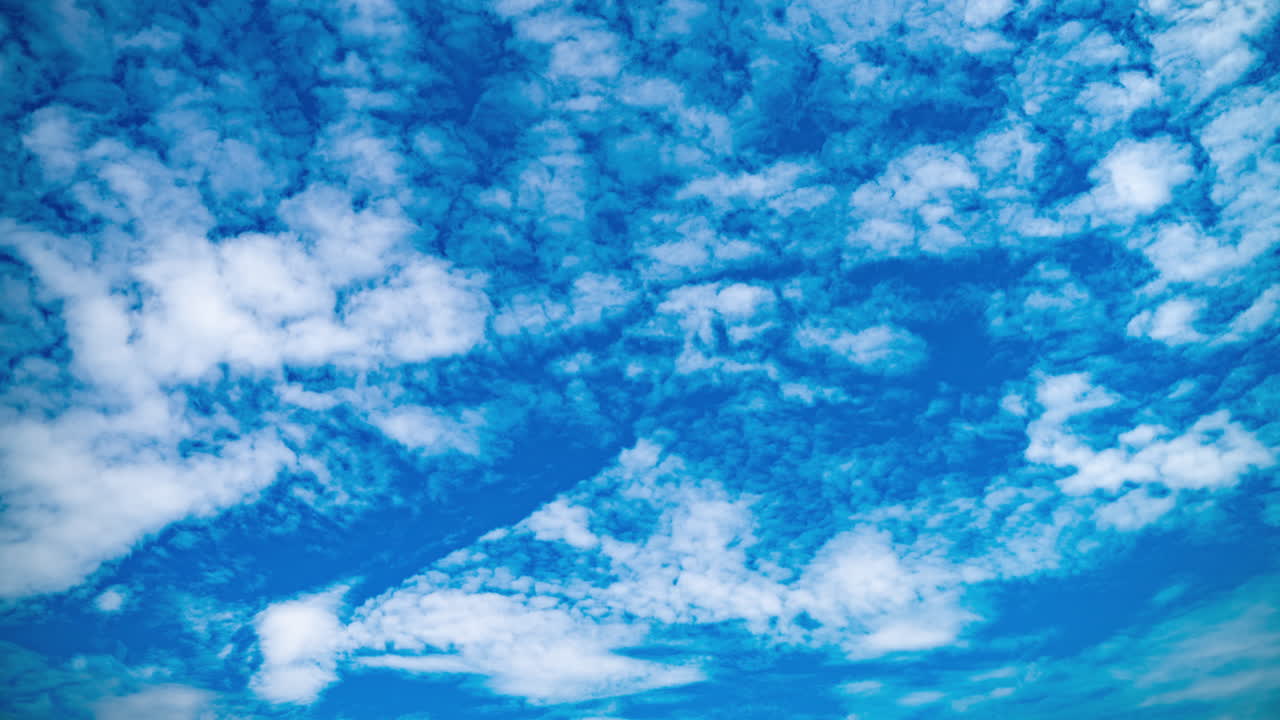 Small white cumulus clouds high in the blue sky. Rapid movement of clouds. Summer timelapse