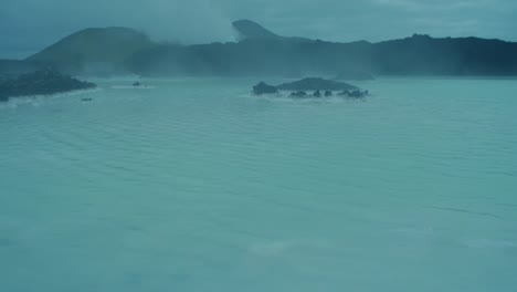 iceland,-blue-lagoon,-Svartsengi-geothermal-power-station-at-night,-mist-rolling-over-the-blue-water,-camera-movement,-camera-tilt-up,-wide-angle-lens-shot