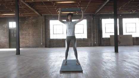 Mujer-Negra-Realizando-Prensas-Sobre-La-Cabeza-En-La-Estera-De-Yoga