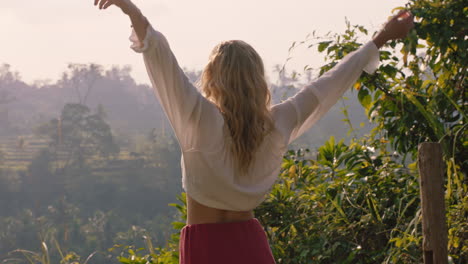 mujer feliz celebrando con los brazos levantados mirando a la selva tropical al amanecer sintiendo alegría en las vacaciones de verano aventura disfrutando de un nuevo día en el paraíso