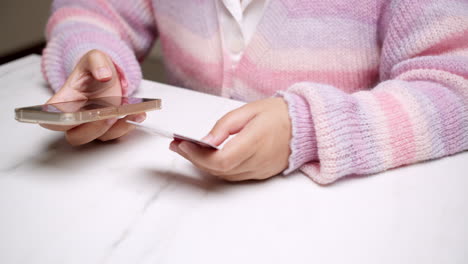 close-up woman's hand holds a smartphone and use a mockup bank credit card for online shopping services to pay money with cashless technology