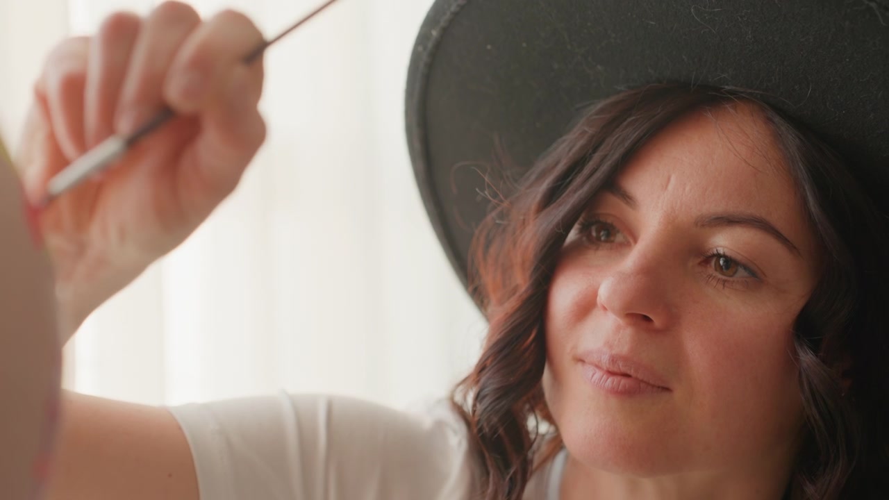 Donna concentrata con cappello che dipinge su tela