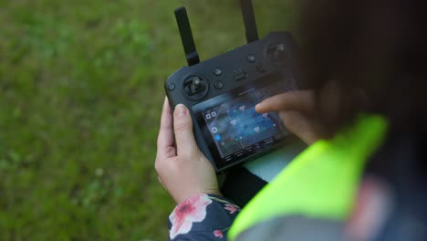 Woman-with-safety-yellow-vest-set-with-fingers-parameters-on-wireless-drone-remote-control