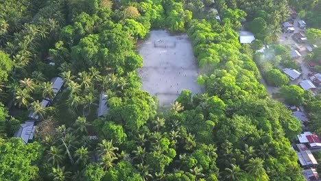 aerial flight towards football field and forest on island in malaysia, wide distance shot moving forward in slow motion