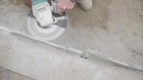 construction worker cutting stone with angle grinder