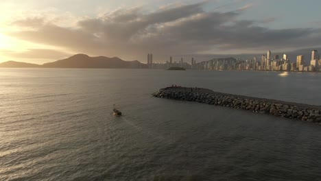 Golden-Hour-Aerial,-Small-Boat-Sailing-into-Balneário-Camboriú-Bay