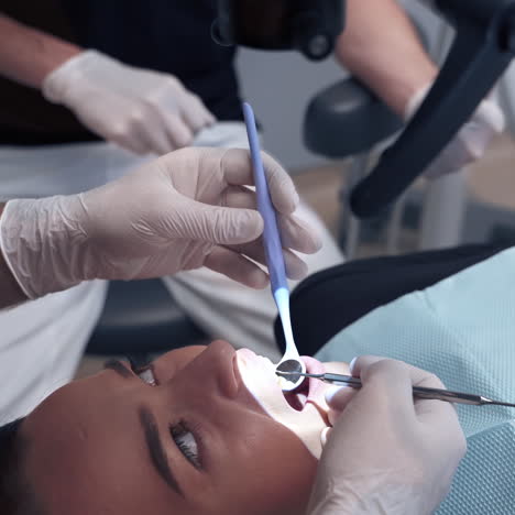 dentist examines patient's teeth through the microscope. specialist looks into female's mouth with medical tools in a dental office.