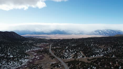 Drone-aerial-view-of-a-remote-highway-with-the-rocky-mountains-in-the-distance
