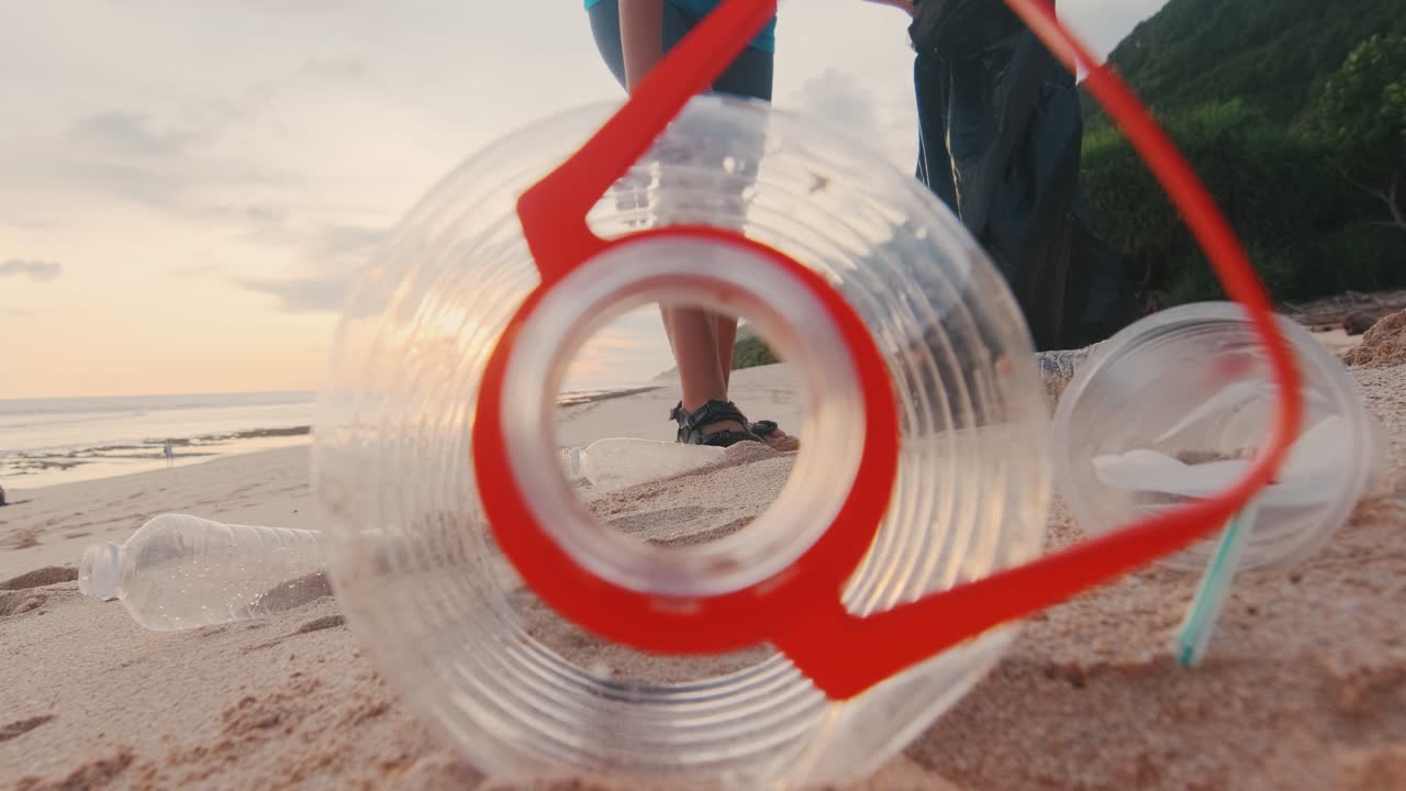 una joven activista ecológica caucásica recoge desechos plásticos en la playa del océano.