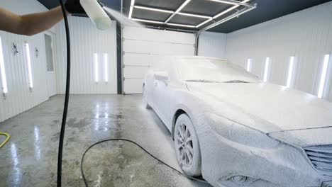 man worker washing red car on a car wash with yellow washcloth.