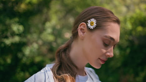 portrait carefree girl posing at green sunny nature with flower behind ear.