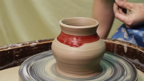 hands on pottery wheel. craftsman artist painting pot with brush