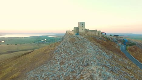 fortaleza de enisala en rumania, disparo de drones, volando lejos de la fortaleza al atardecer
