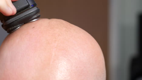 hombre afeitándose la cabeza calva con maquinilla de afeitar eléctrica