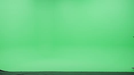 green screen studio: strong indian man wearing casual clothes and duffel bag, uses smartphone device, dealing with business, talking to a girlfriend walks across chroma key room. side view camera shot