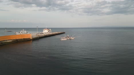 dolly aéreo al amanecer del puerto de taloot argao en cebu, filipinas, con barcos atracados cerca de la costa y el paisaje oceánico circundante